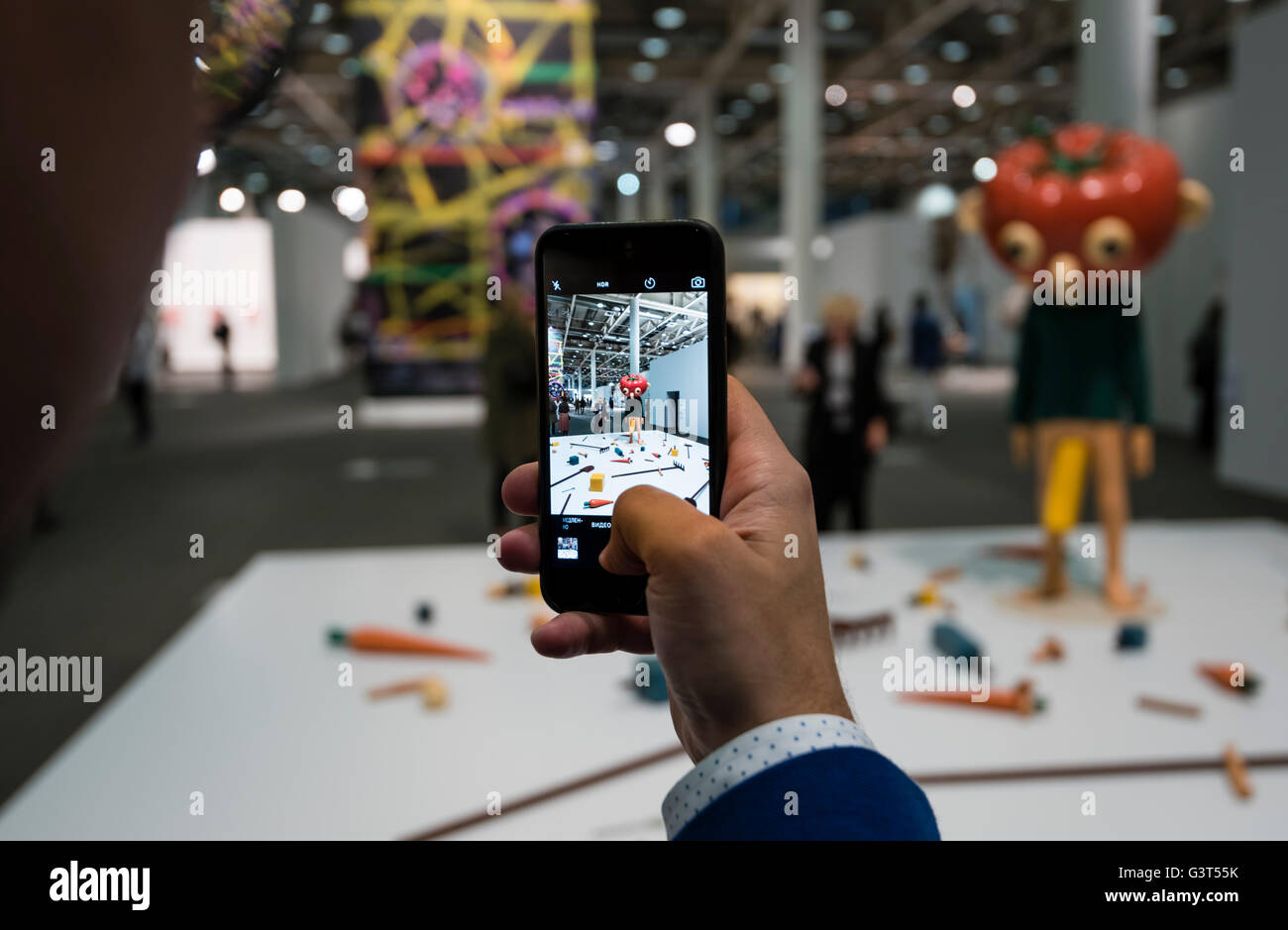 Basel, Switzerland. 14 June, 2016. A visitor is taking a picture of the sculpture 'Tomato Head (Green)' by Paul McCarthy at the opening of the modern art show 'Art Basel 2016' in Basel, Switzerland. With 280 galleries showing works from 4,000 artists, Art Basel is one of the world's largest and most spectacular gatherings for contemporary and modern art. In 2015, the show in Basel (which also has offshoots in Hong Kong and Miami) attracted 98,000 visitors from all over the world. Credit:  Erik Tham/Alamy Live News Stock Photo