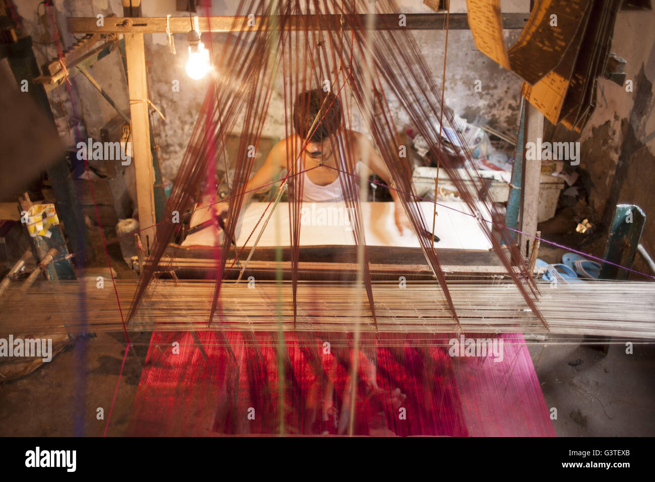 Dhaka, Bangladesh. 15th June, 2016. Handloom weaver weaves Banarasi saree on a traditional wooden hand weaving loom at Mirpur Banarasi Palli, in Dhaka, Bangladesh. Business in Mirpur Banarasi Palli, a market place well-known for different kinds of traditional Banarasi Sarees in Bangladesh, is facing tough times. People, who used to go there to purchase the famous Banarasi sarees, are increasingly opting for trendy Indian sarees. The popularity of these custom-made sarees is losing its charm as colorful Indian chic sarees are more in demand among local buyers. The Benarasi saree, whose history Stock Photo