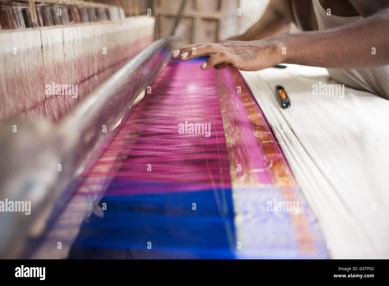 Dhaka, Bangladesh. 15th June, 2016. Handloom weaver weaves Banarasi saree on a traditional wooden hand weaving loom at Mirpur Banarasi Palli, in Dhaka, Bangladesh. Business in Mirpur Banarasi Palli, a market place well-known for different kinds of traditional Banarasi Sarees in Bangladesh, is facing tough times. People, who used to go there to purchase the famous Banarasi sarees, are increasingly opting for trendy Indian sarees. The popularity of these custom-made sarees is losing its charm as colorful Indian chic sarees are more in demand among local buyers. The Benarasi saree, whose history Stock Photo