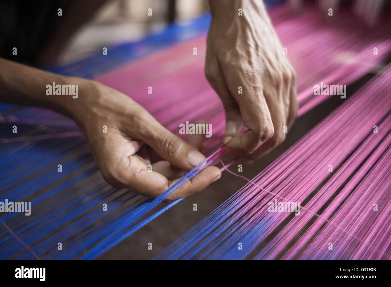 Dhaka, Bangladesh. 15th June, 2016. Handloom weaver weaves Banarasi saree on a traditional wooden hand weaving loom at Mirpur Banarasi Palli, in Dhaka, Bangladesh. Business in Mirpur Banarasi Palli, a market place well-known for different kinds of traditional Banarasi Sarees in Bangladesh, is facing tough times. People, who used to go there to purchase the famous Banarasi sarees, are increasingly opting for trendy Indian sarees. The popularity of these custom-made sarees is losing its charm as colorful Indian chic sarees are more in demand among local buyers. The Benarasi saree, whose history Stock Photo