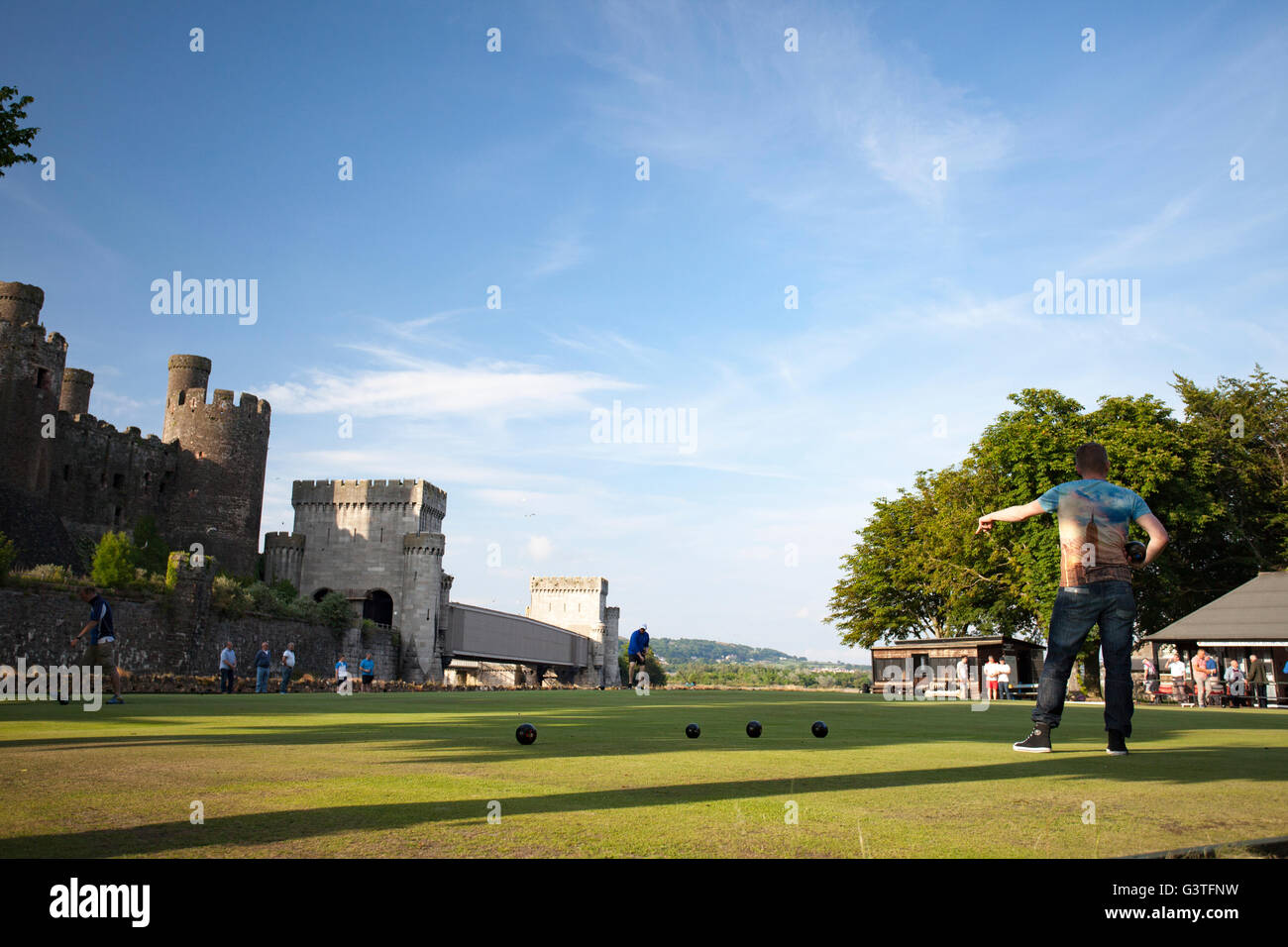 Conwy Bowling Club a crown green bowling venue next to the majestic medieval Conwy Castle on a hot summers evening with bowlers passing the time away relaxing on the green, Conwy, Wales, UK Stock Photo