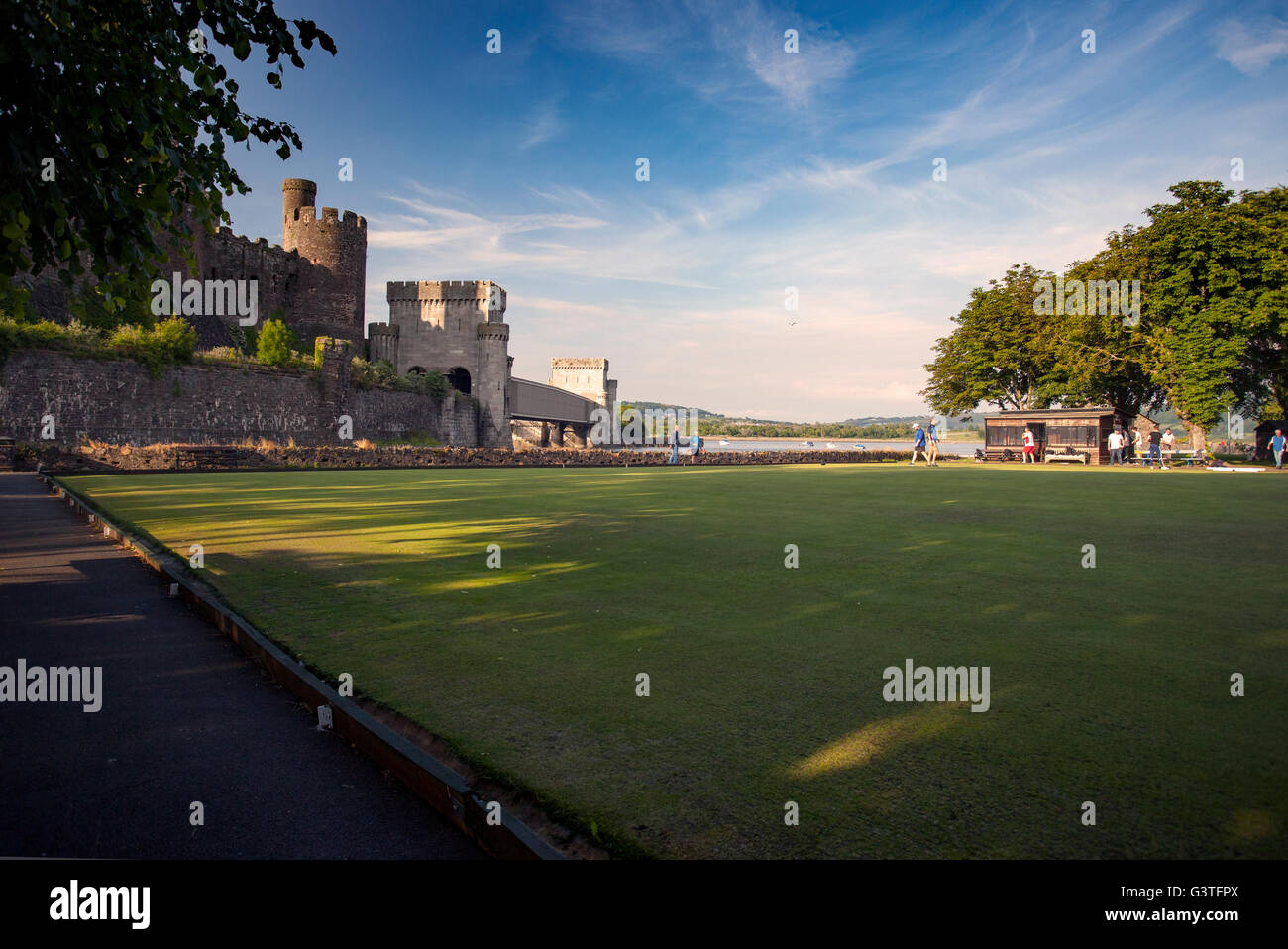 Cowny Bowling Club a crown green bowling venue next to the majestic medieval Conwy Castle on a hot summers evening with bowlers passing the time away relaxing on the green, Conwy, Wales, UK Stock Photo