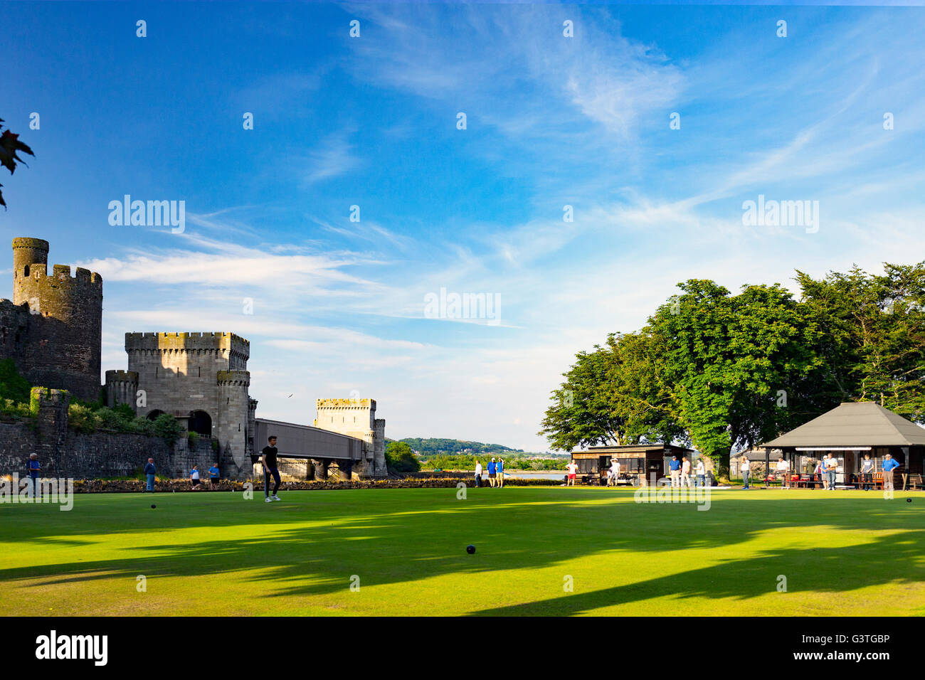 Conwy Bowling Club a crown green bowling venue next to the majestic medieval Conwy Castle on a hot summers evening with bowlers passing the time away relaxing on the green, Cowny, Wales, UK Stock Photo