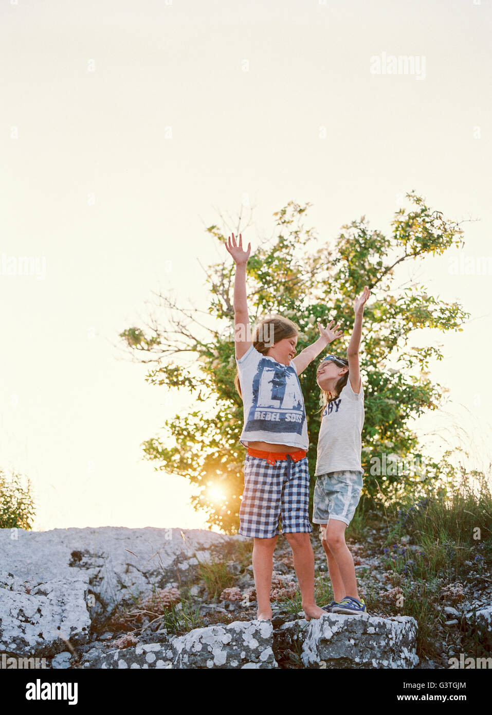 Sweden, Two boys (8-9, 10-11) standing on rock with hands up Stock Photo
