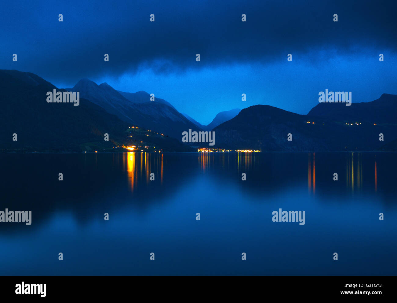 Norway, More og Romsdal, Eidsdal, Still lake and reflections of illuminated towns on opposite shore Stock Photo
