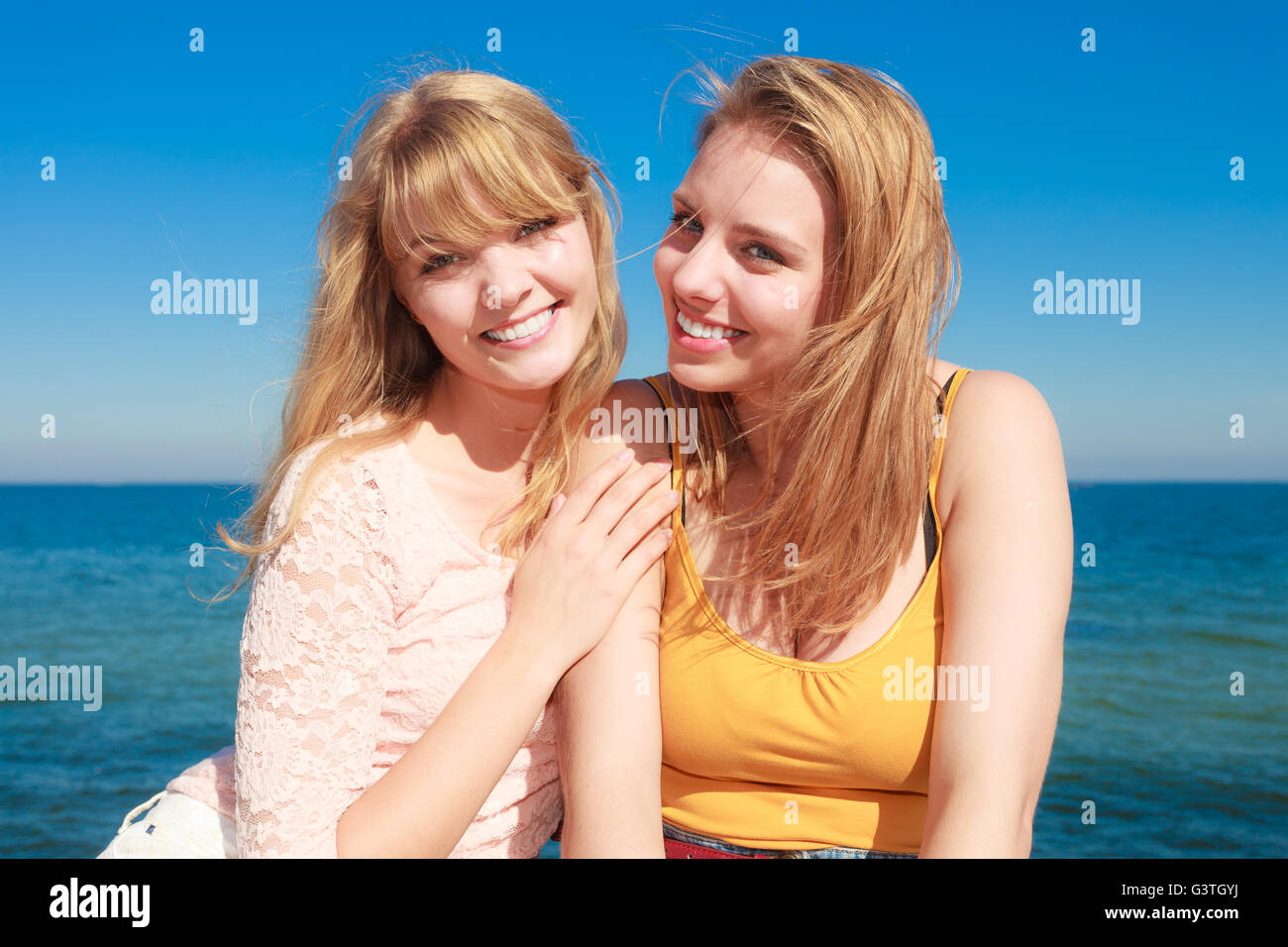Two young women best friends blonde cheerful girls having fun outdoor wind blowing in hair. Summer happiness friendship concept. Stock Photo