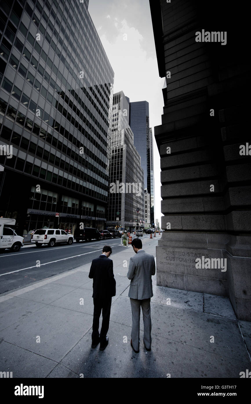 USA, New York State, New York City, Wall Street, Two businessmen standing in street Stock Photo