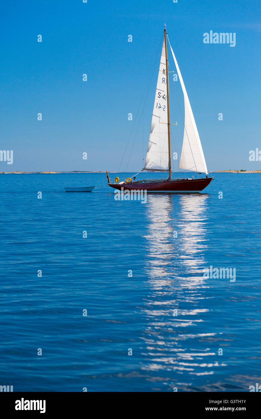 Sweden, Uppland, Stockholm Archipelago, Sailboat pulling smaller boat Stock Photo