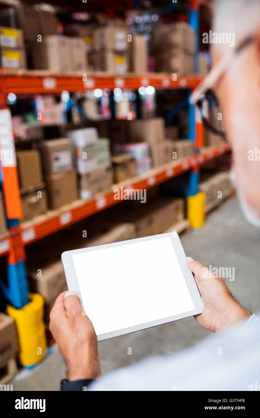Rear view of warehouse manager looking his tablet computer Stock Photo
