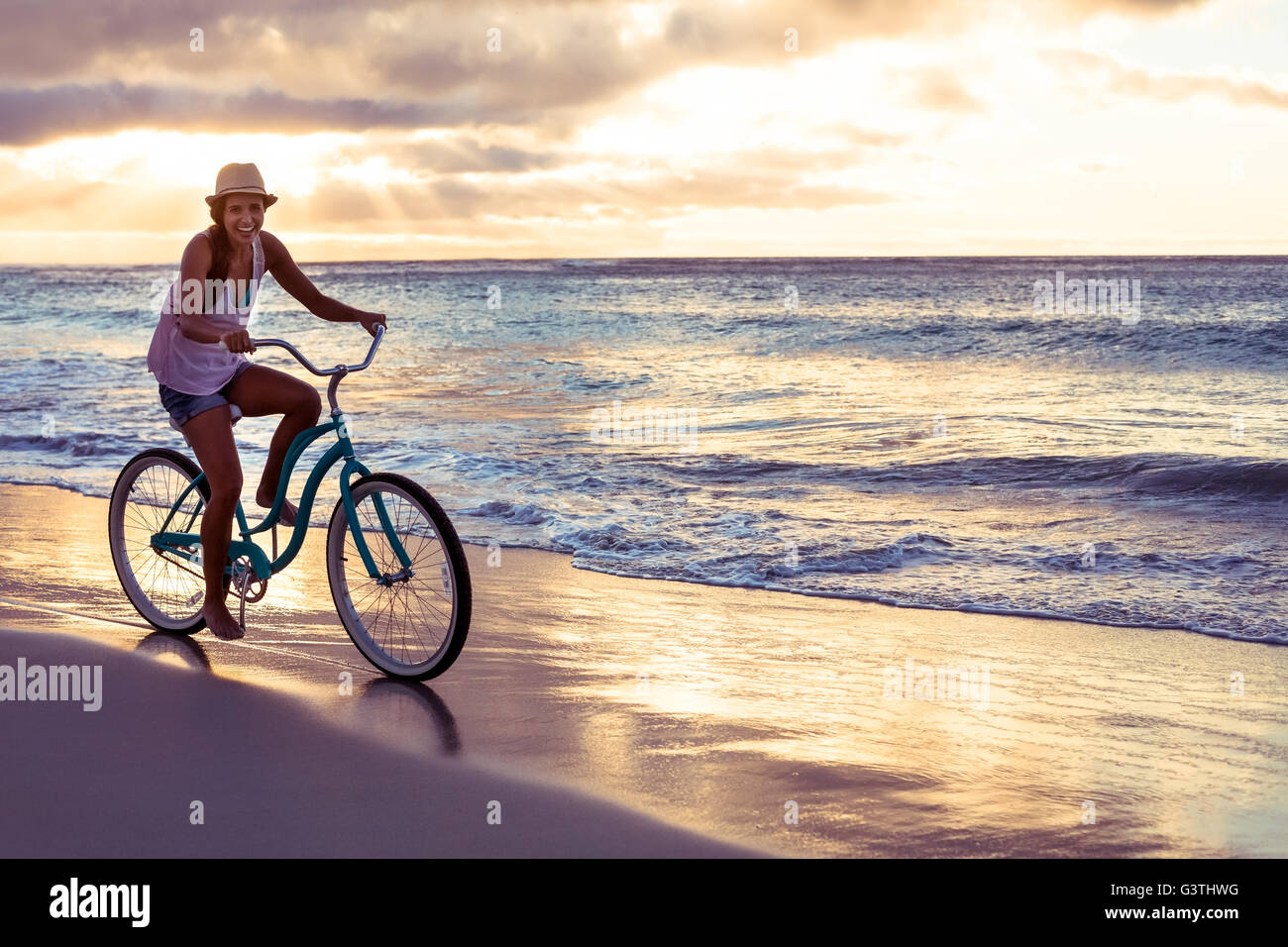 Woman cycling on the beach Stock Photo