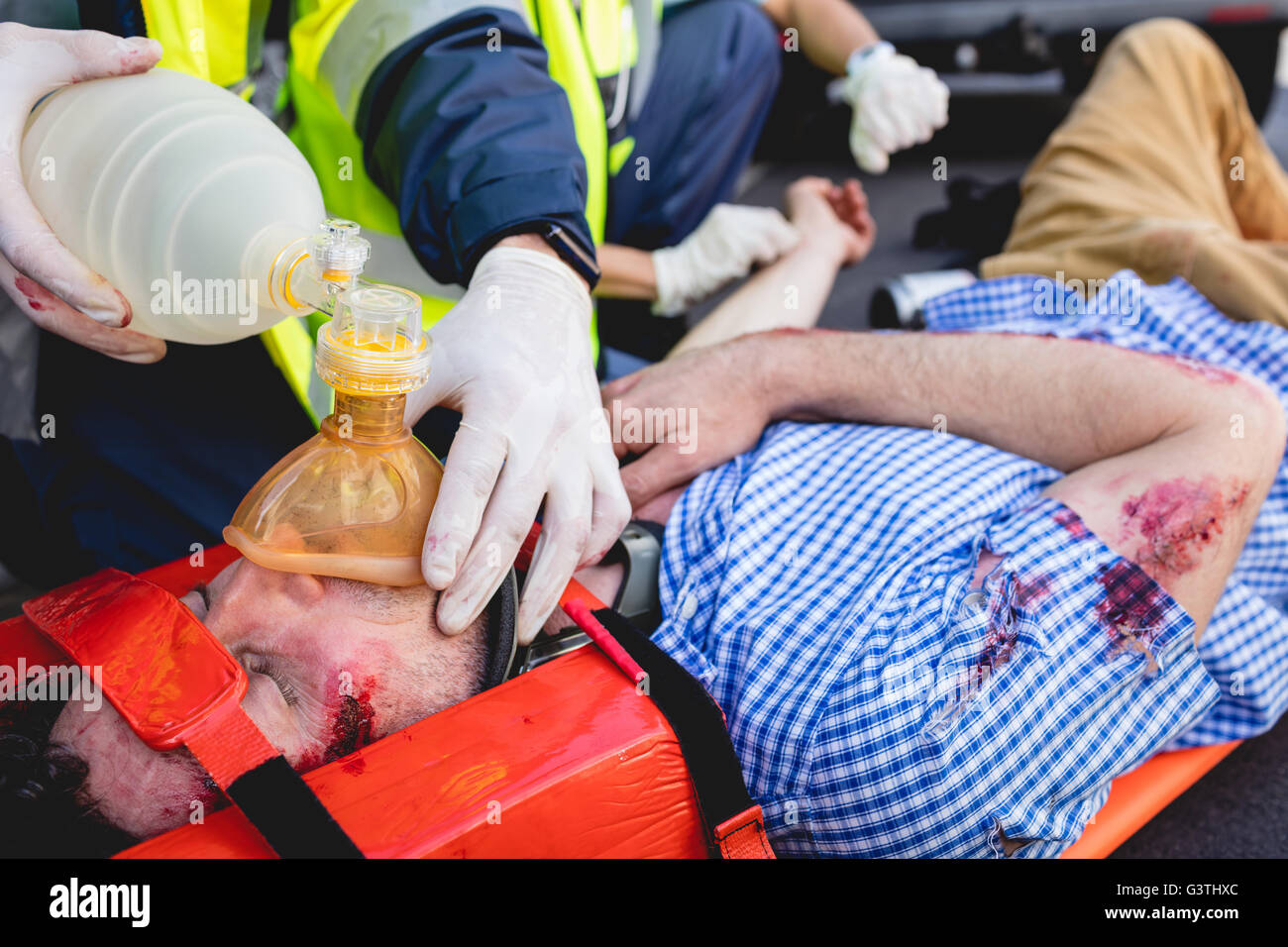 Ambulancemen healing injured man Stock Photo