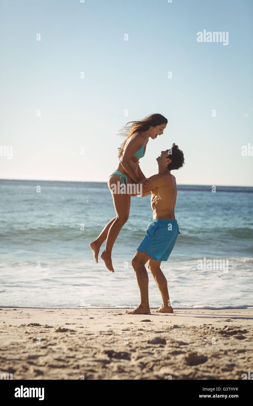 Man lifting woman on beach Stock Photo