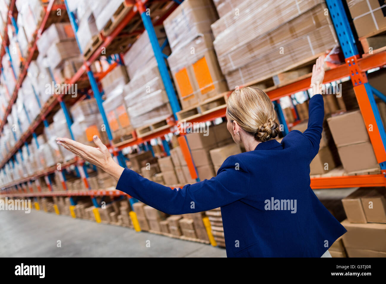 Side view of warehouse manager raising her arms Stock Photo