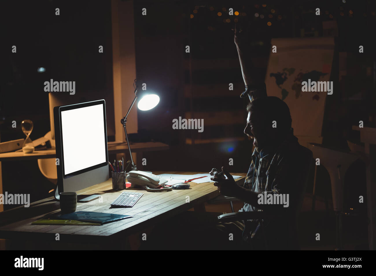 Businessman playing computer games at night Stock Photo