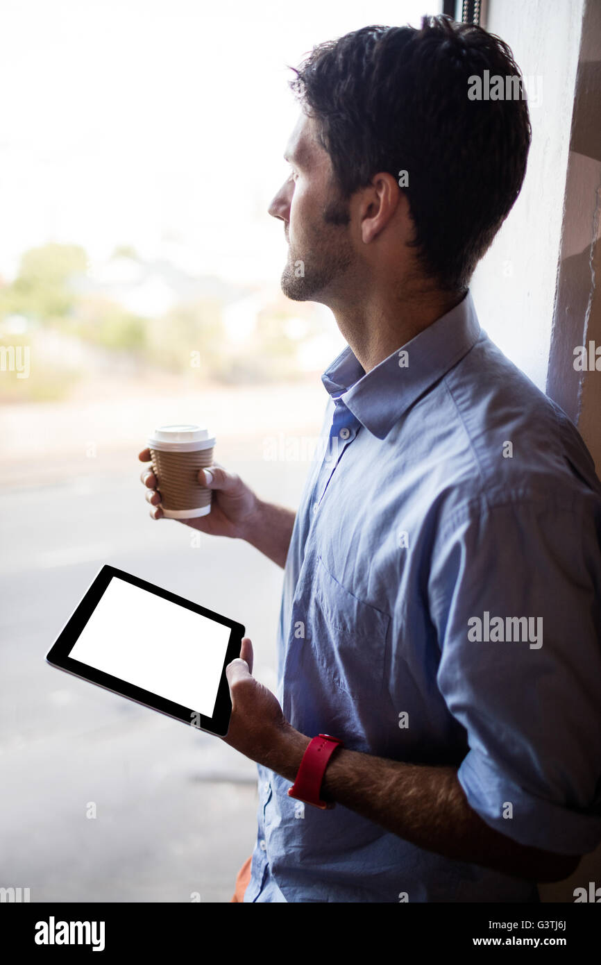 Profile view of businessman is holding a tablet and a coffee Stock Photo