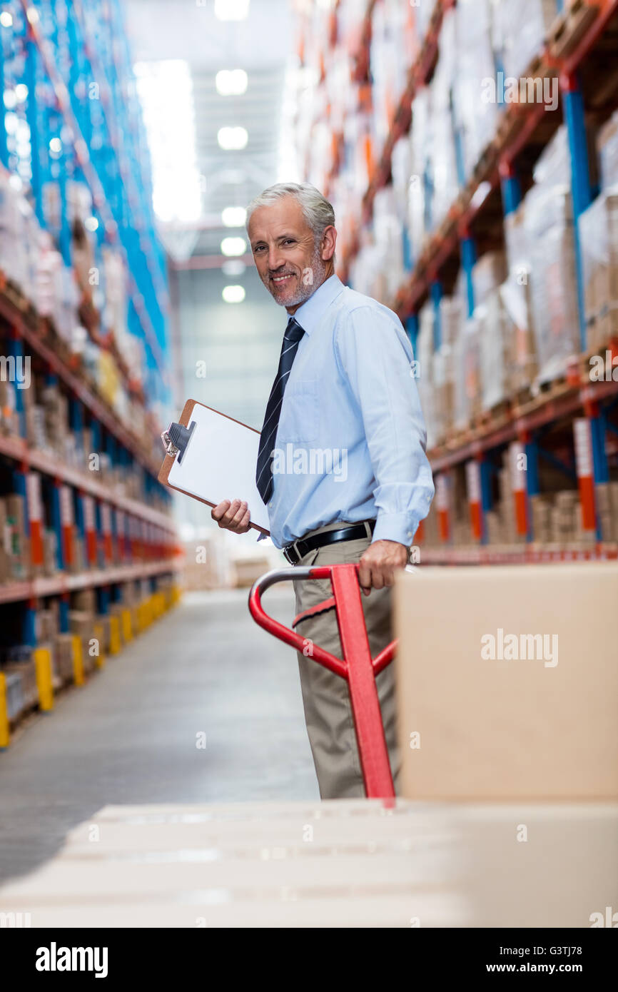 Smiling warehouse manager with clipboard and pallet truck Stock Photo