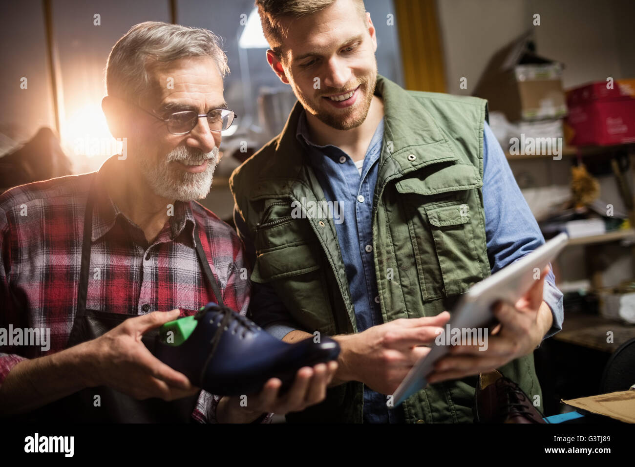 Cobblers smiling and holding a shoe and tablet computer Stock Photo