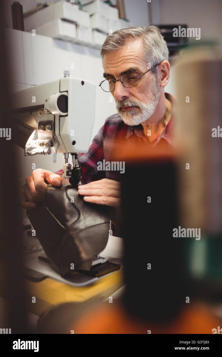 Focus on background of cobbler using sewing machine Stock Photo