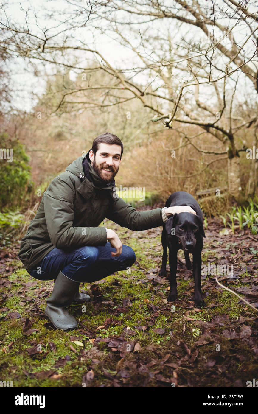 Hipster man smiling at camera while stroking his dog Stock Photo