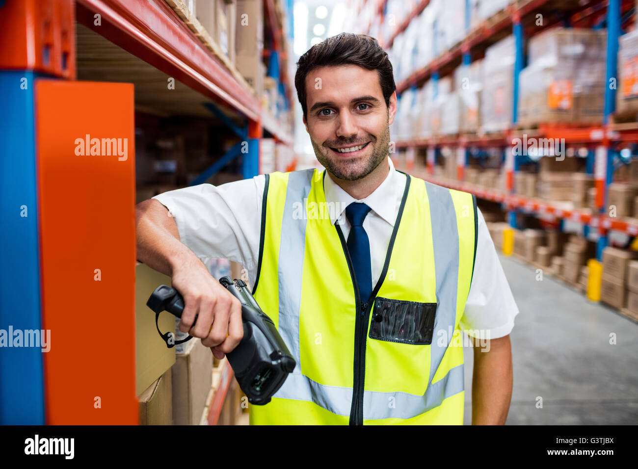 Smiling warehouse manager with yellow coat and scanner Stock Photo