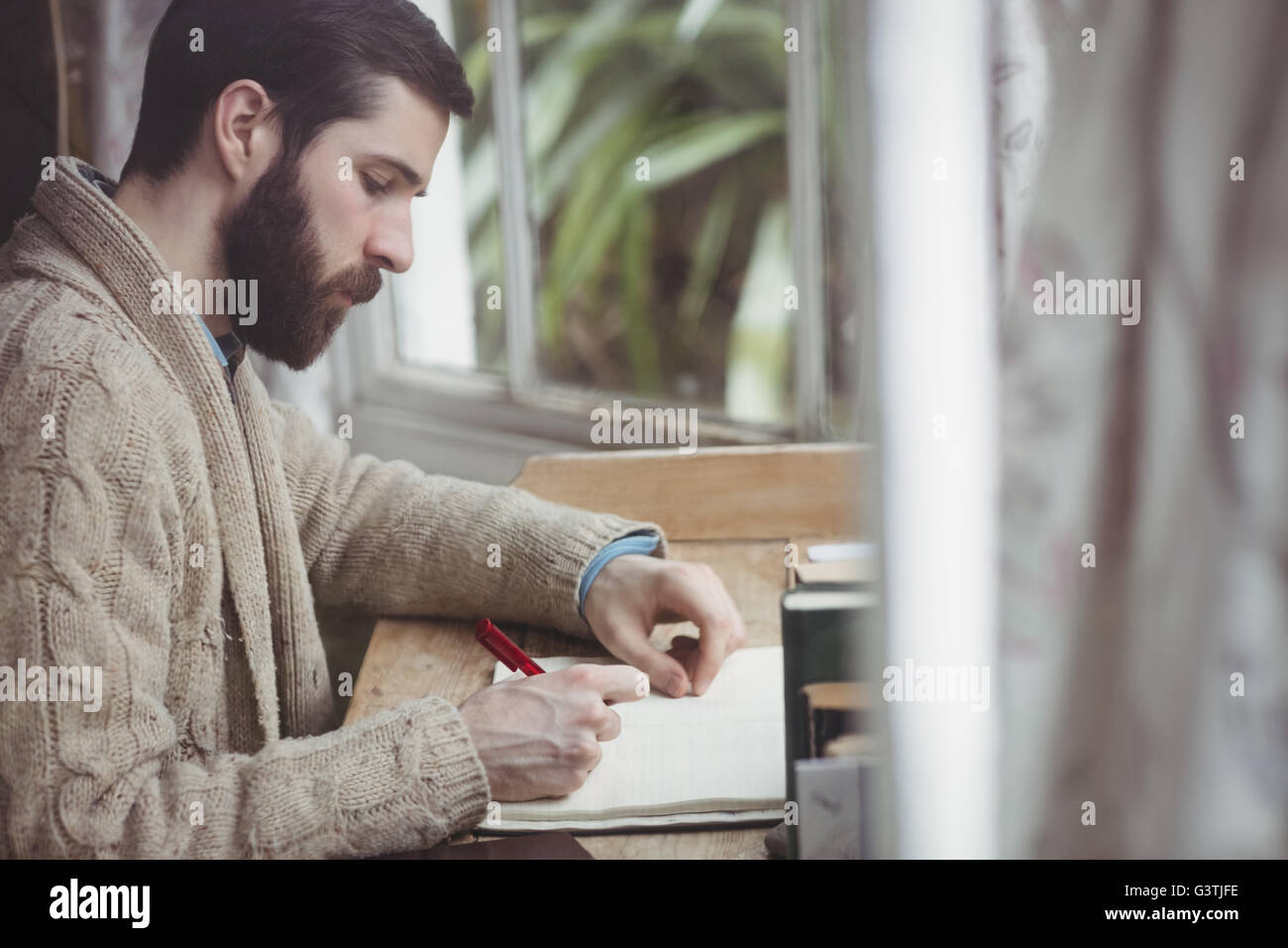Profile of hipster writing in a notebook Stock Photo