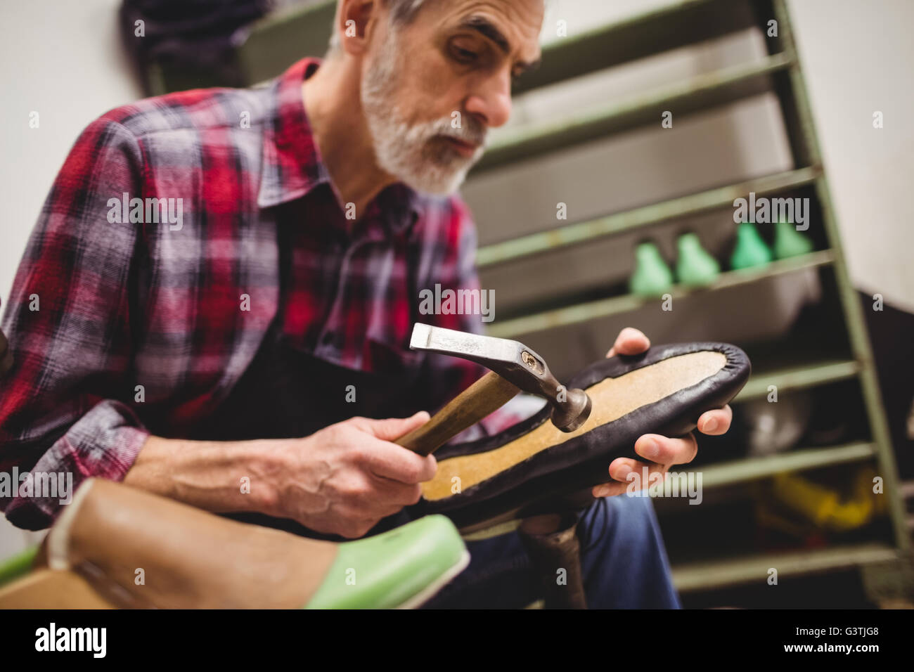 Cobbler hammering on the sole of a shoe Stock Photo