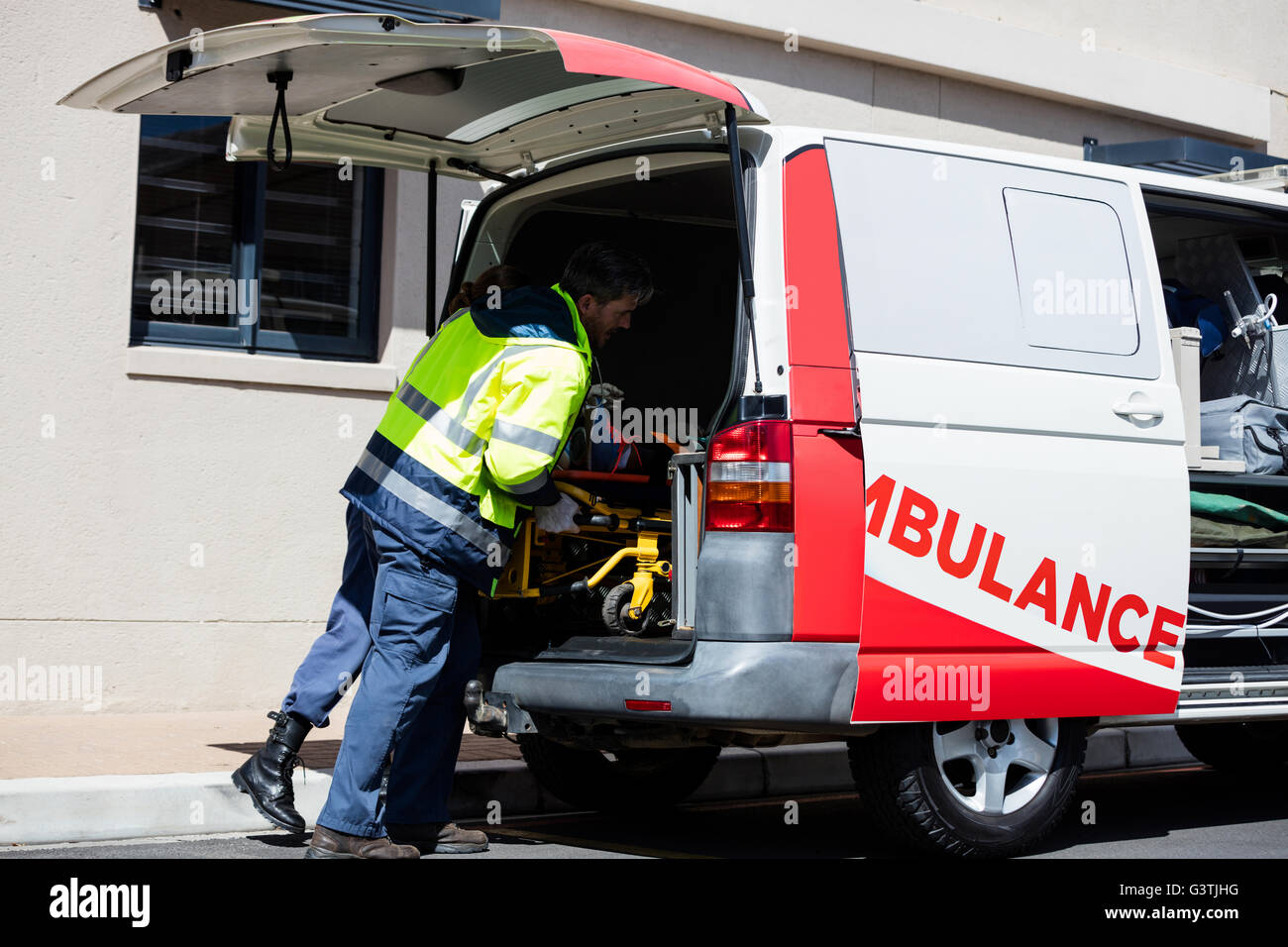 Ambulance men bringing injured people inside ambulance car Stock Photo