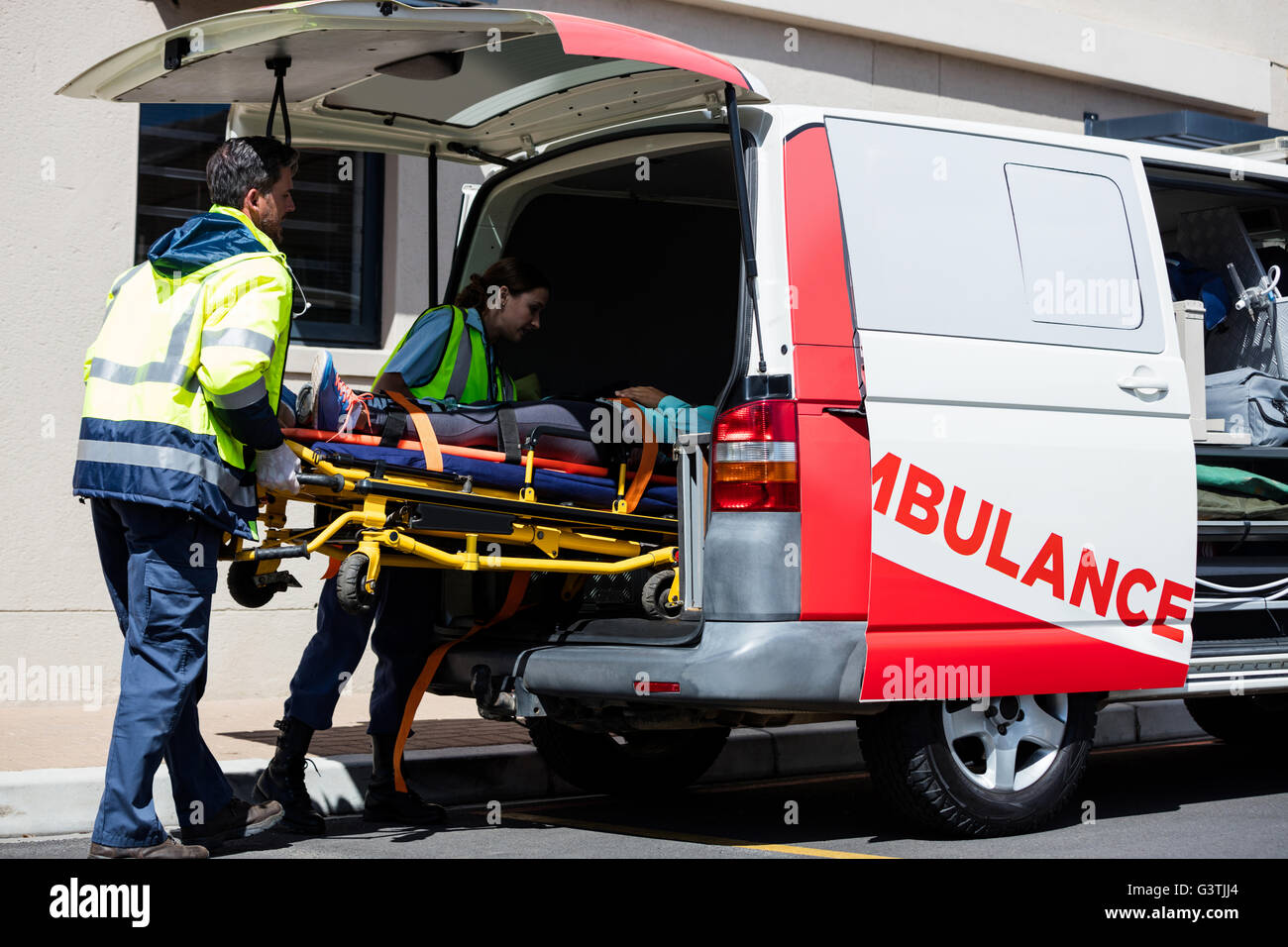 Ambulance men bringing injured people inside ambulance car Stock Photo