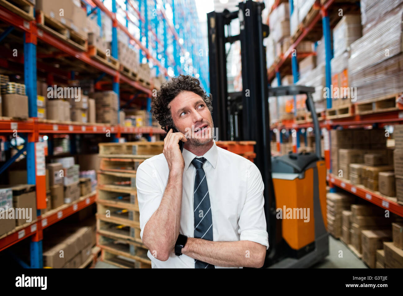 Warehouse manager giving phone call next to a forklift Stock Photo