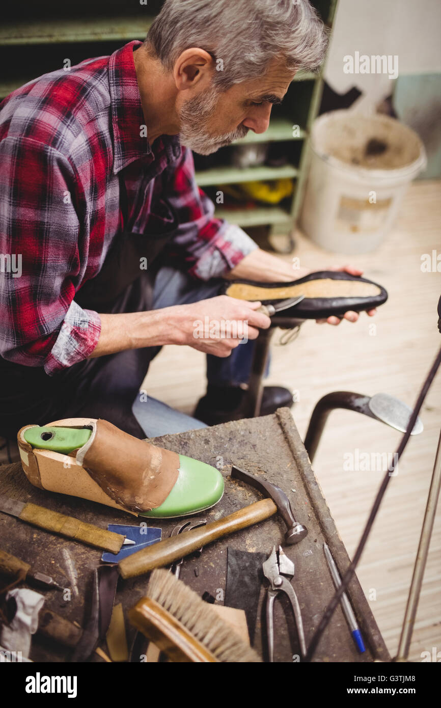 Profile view of cobbler using knife on a shoe Stock Photo