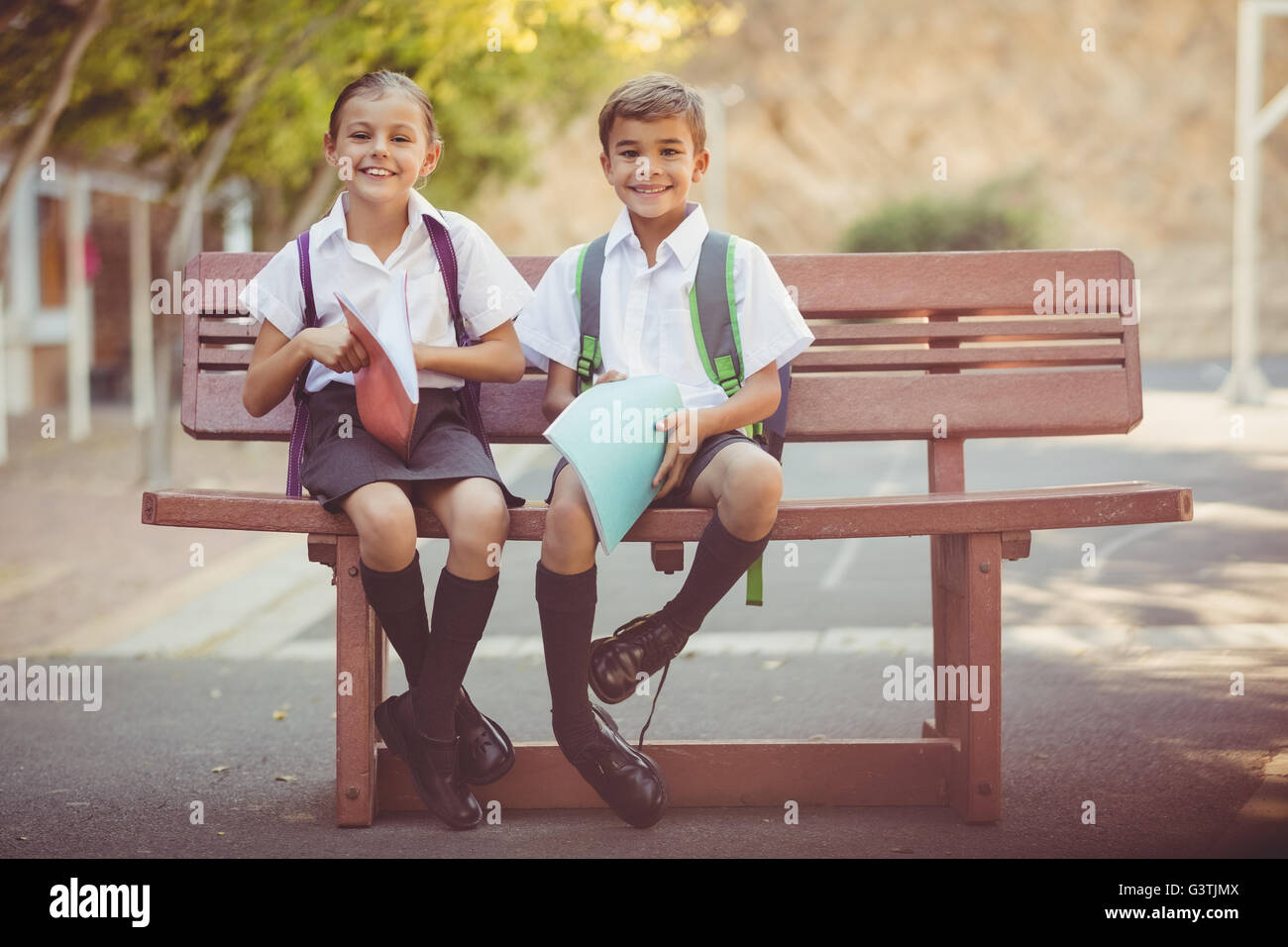 Portrait of smiling school kids sitting on bench Stock Photo Alamy