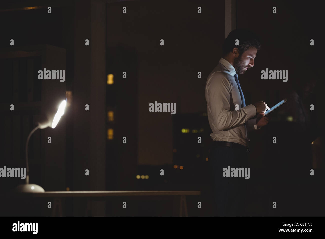 Businessman using tablet at night Stock Photo - Alamy