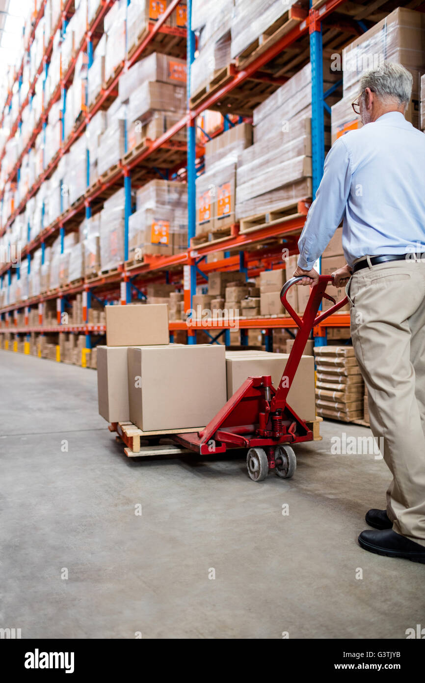 Warehouse manager in aisle with a pallet truck Stock Photo