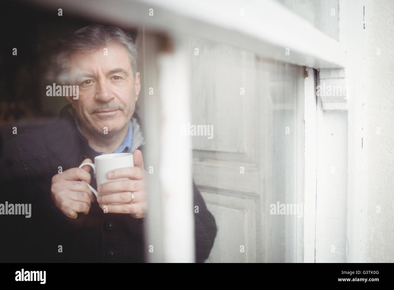 Facing view of mature man looking through window Stock Photo