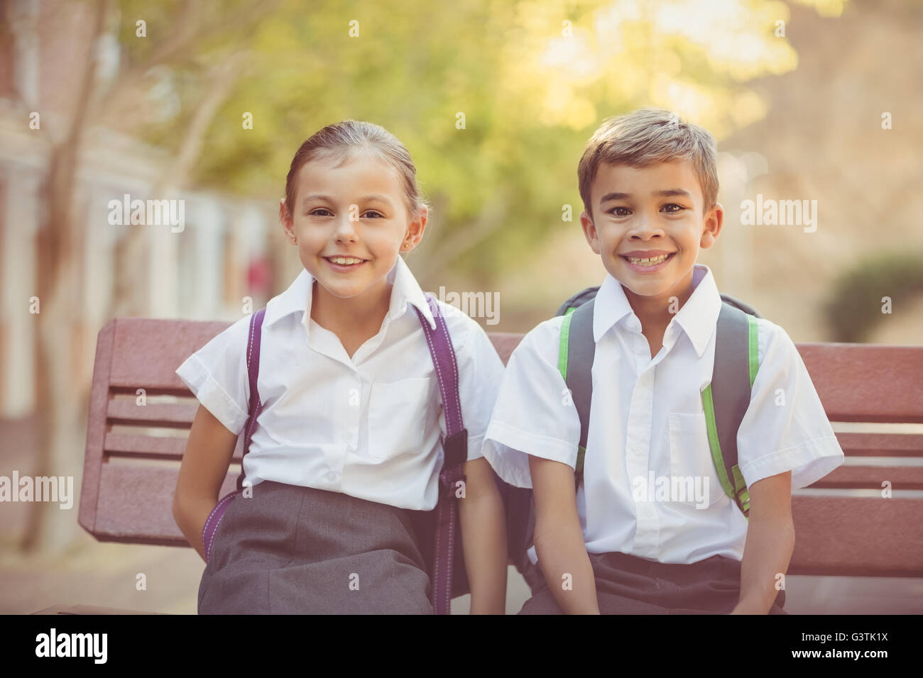 Portrait of smiling school kids sitting on bench Stock Photo Alamy