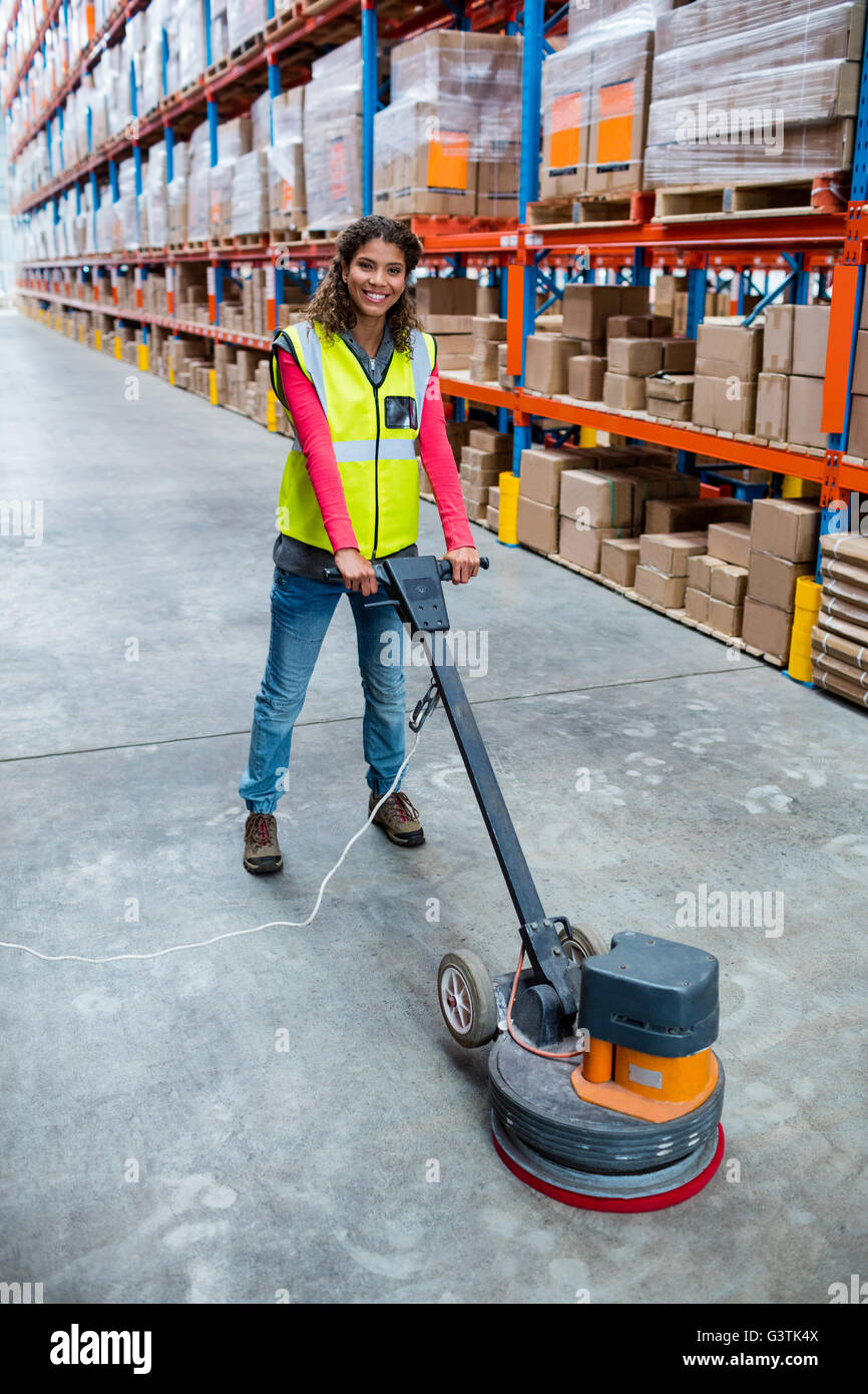 Woman cleaning warehouse floor with machine Stock Photo