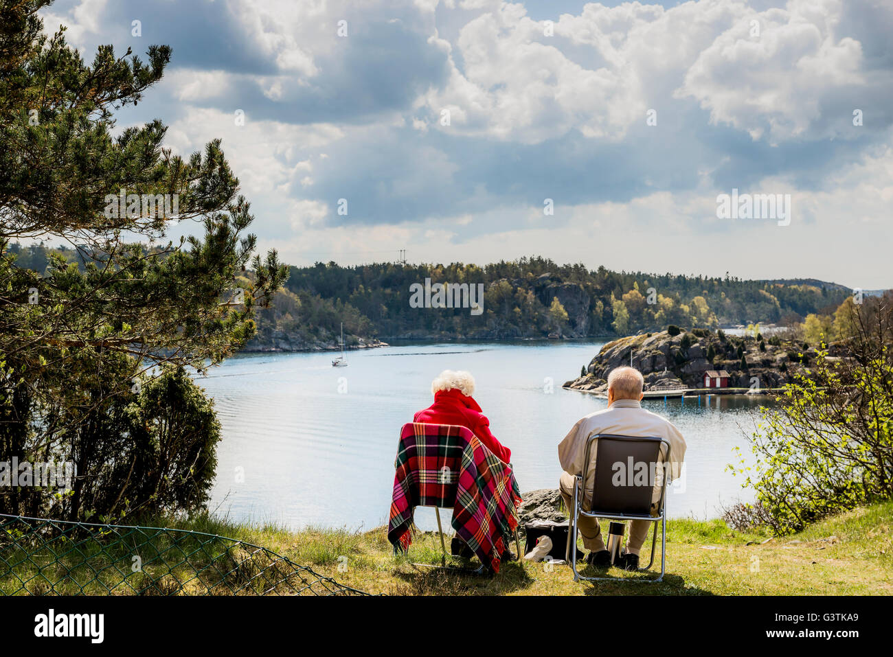 Sweden, West Coast, Bohuslan, Senior couple sitting on lounge chairs and looking at view Stock Photo