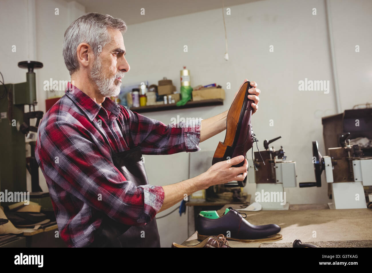 Profile view of cobbler examining a shoe Stock Photo - Alamy