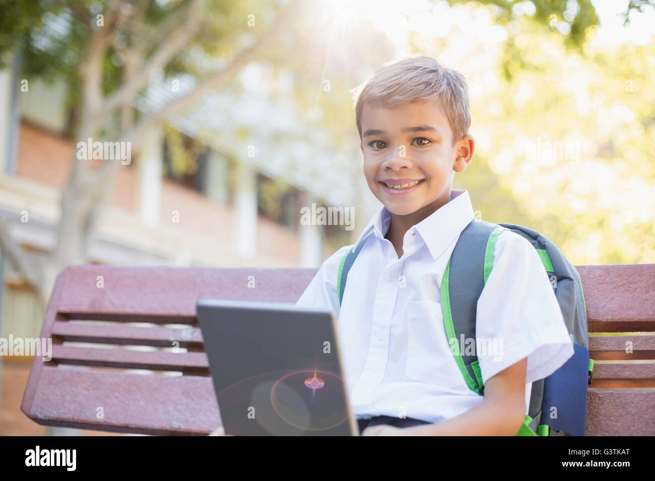 Happy schoolboy sitting on bench with digital tablet Stock Photo - Alamy