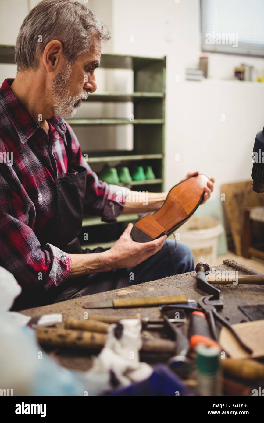 Profile view of cobbler looking the sole of a shoe Stock Photo