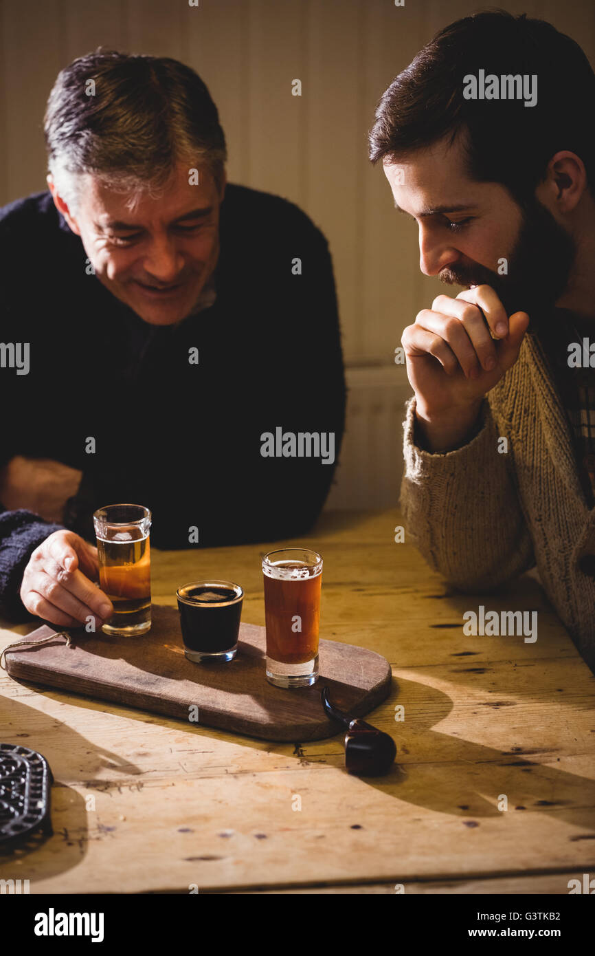 Portrait of hipster ans mature man looking at shots on the table Stock Photo