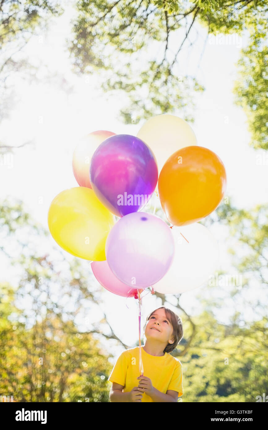 Smiling boy holding a balloon in park Stock Photo