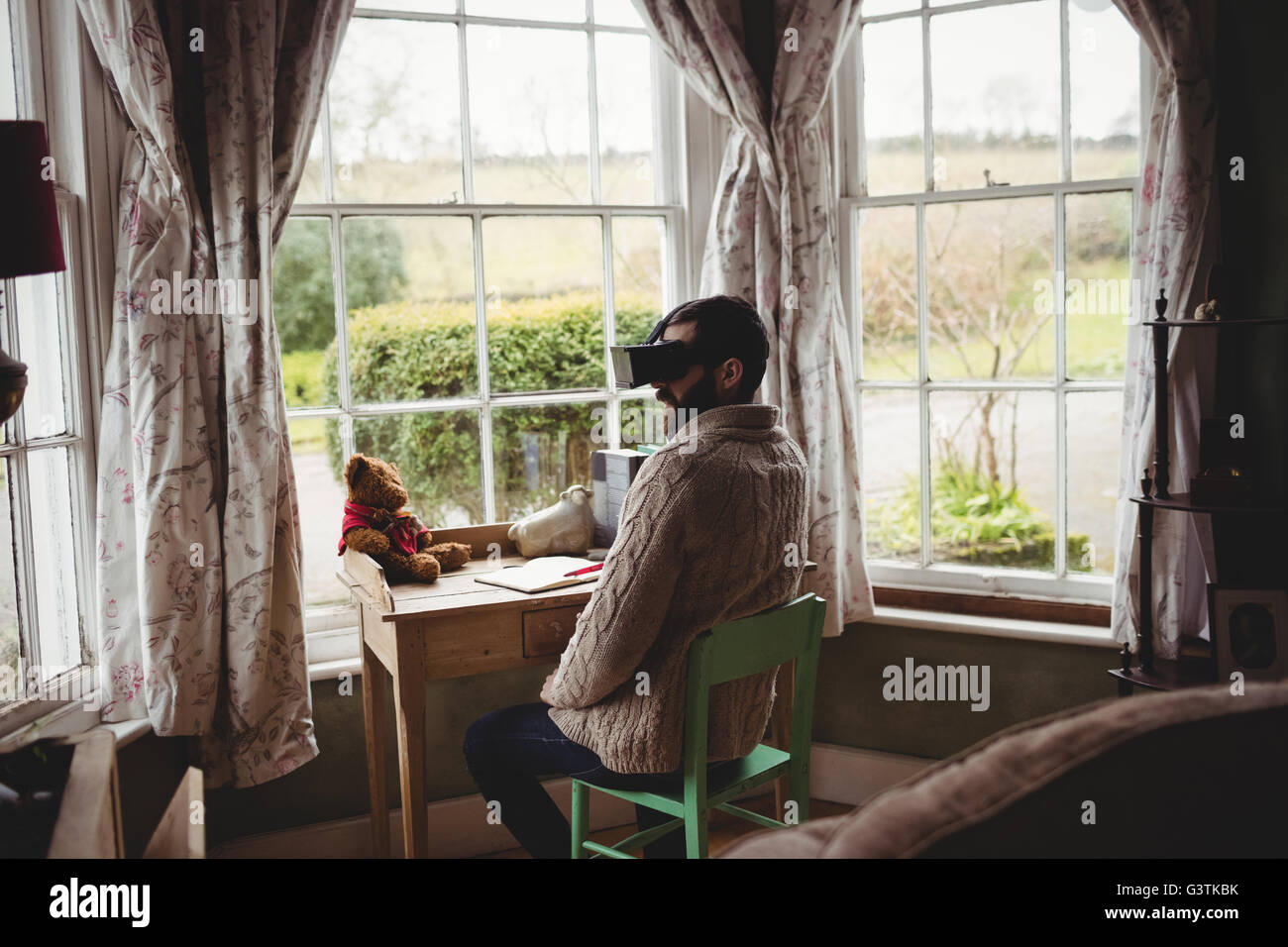 Hipster man using smart glasses while seating at desk Stock Photo