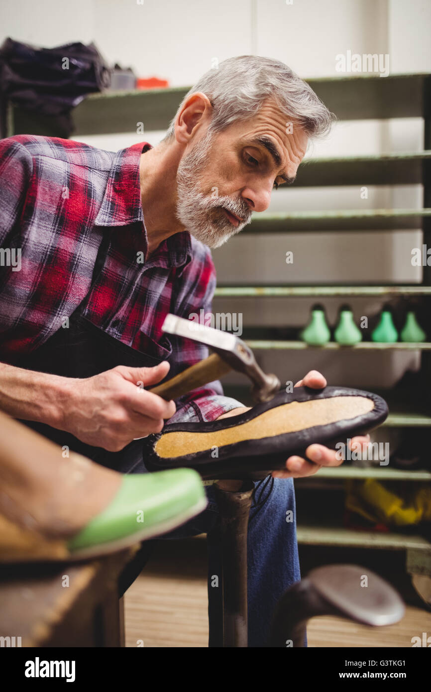 Side view of cobbler hammering on the sole of a shoe Stock Photo