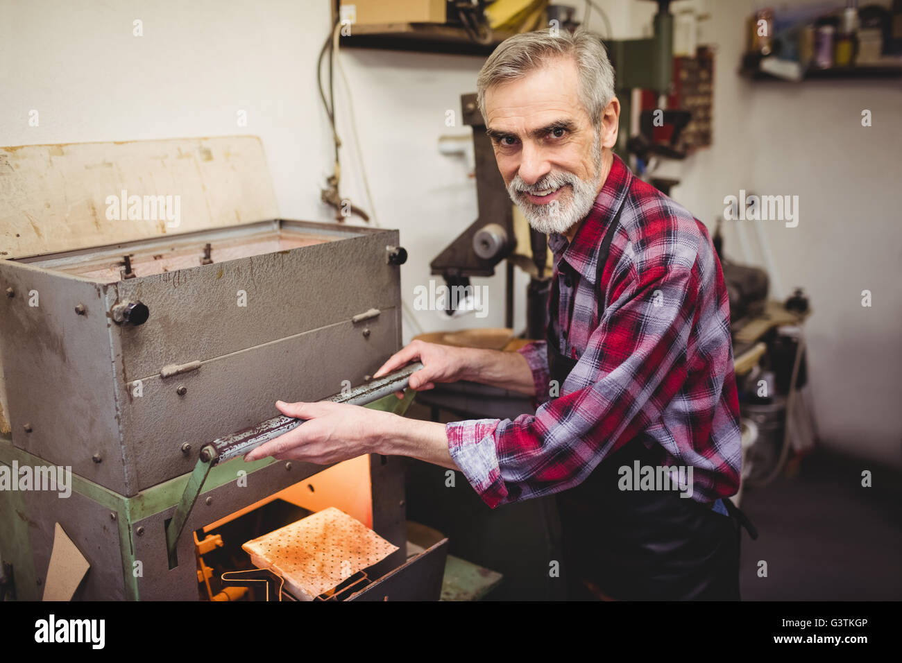 Portrait of cobbler smiling next to a machine Stock Photo