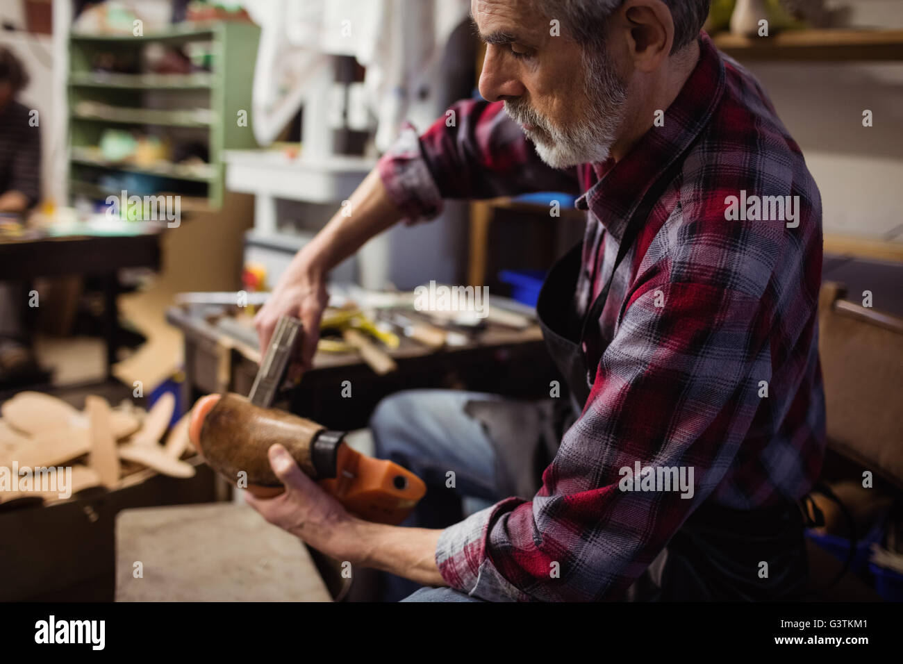 Profile view of cobbler stapling a shoe Stock Photo