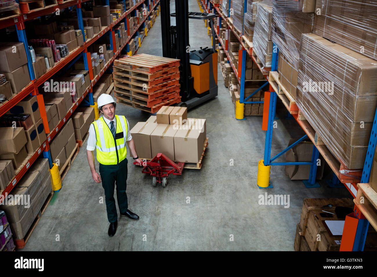 Portrait of a warehouse manager with forklift and pallet truck Stock Photo