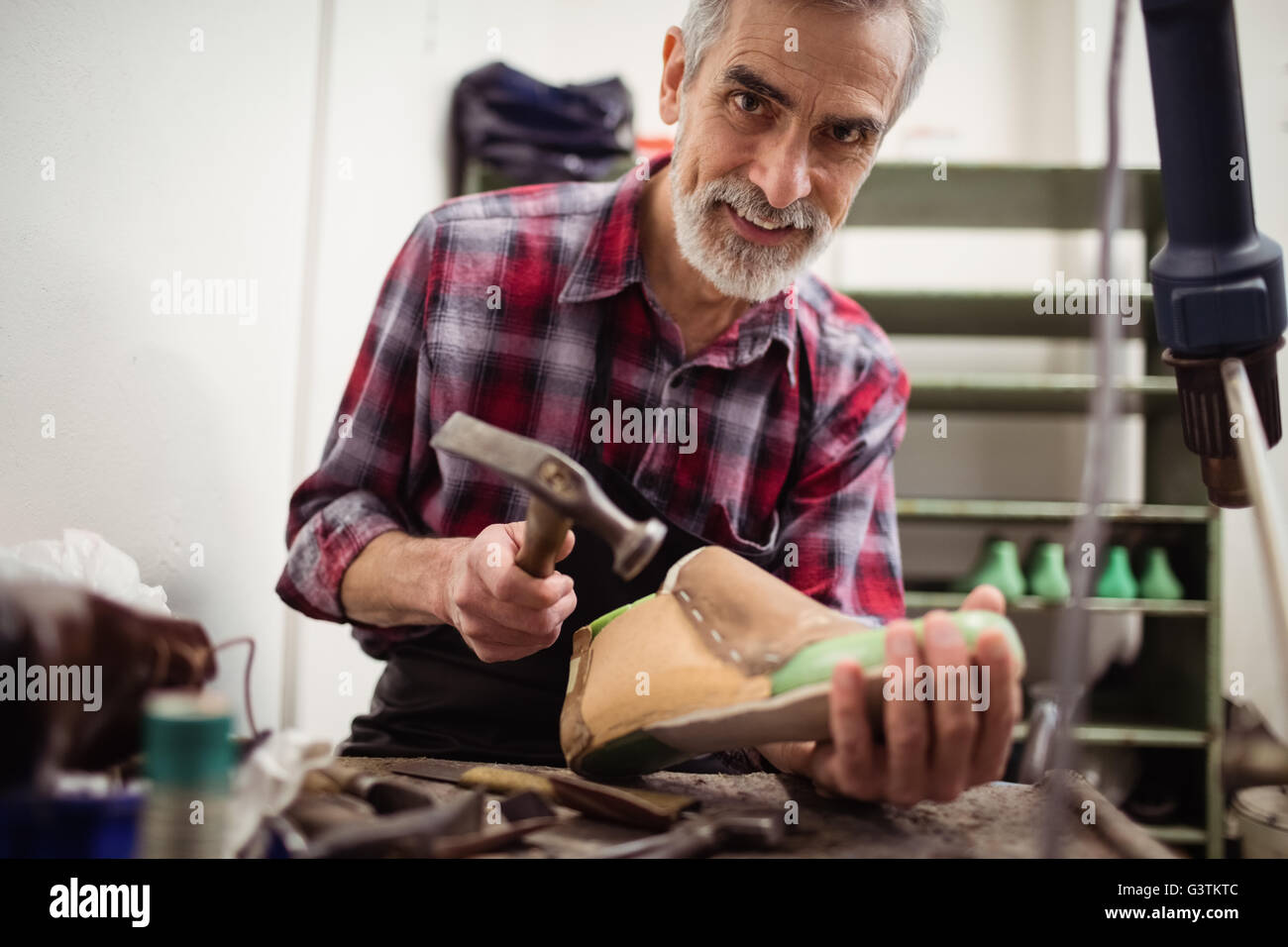 Cobbler smiling and hammering on a shoe Stock Photo