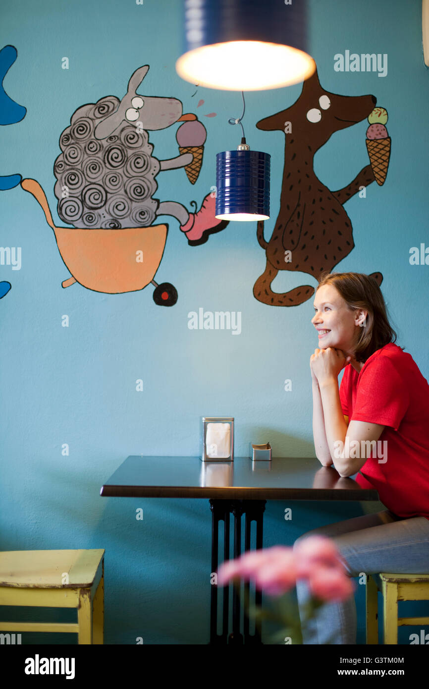 Finland, Smiling woman sitting at table in cafe Stock Photo