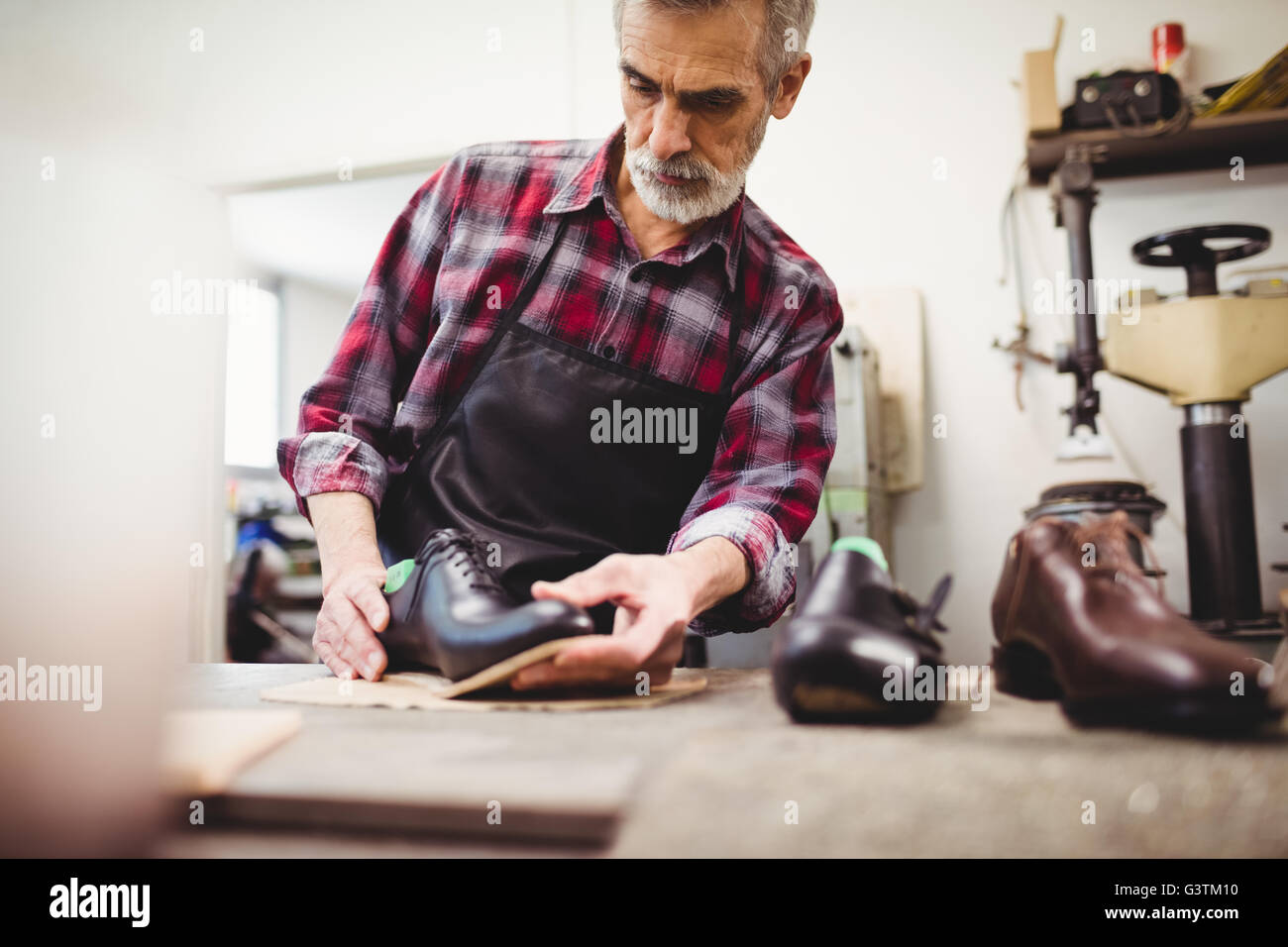 Concentrated cobbler looking a shoe Stock Photo